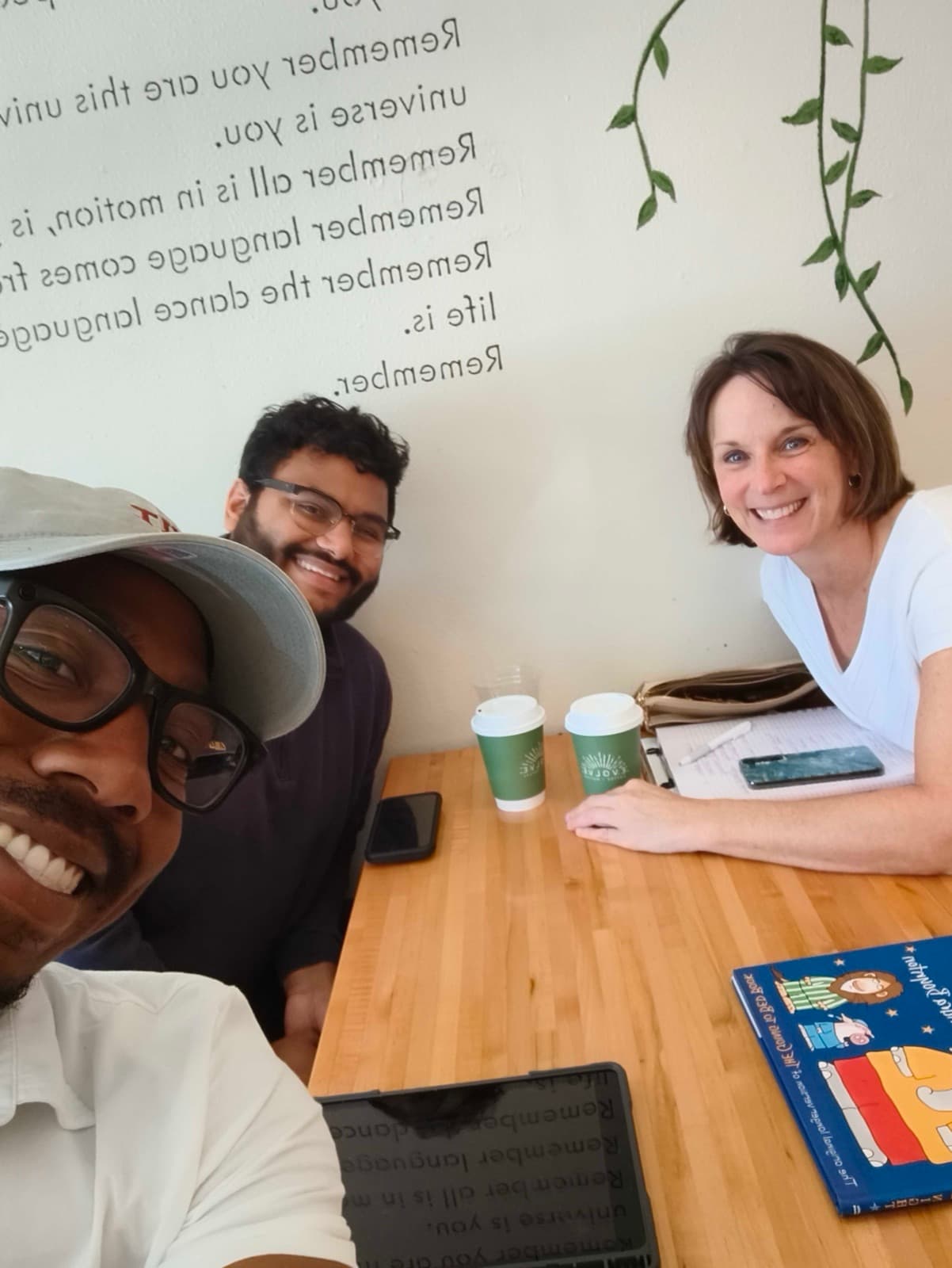 Akintunde and Shivang at a café table with speech-language pathologist Lori Reyes